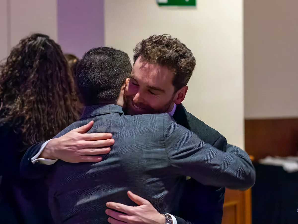 Dos invitados se abrazan durante la gala, con otra asistente a su lado